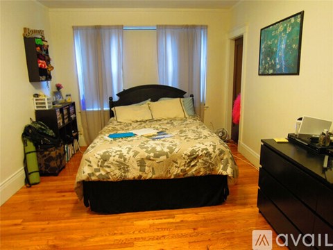 A bedroom with a bed, nightstand, and a painting on the wall.