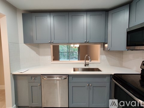 A kitchen with grey cabinets and a stainless steel dishwasher.