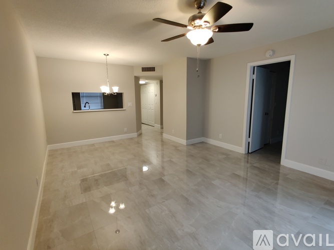 A spacious room with a ceiling fan and a flat screen TV mounted on the wall.