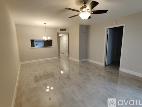 A spacious room with a ceiling fan and a flat screen TV mounted on the wall.