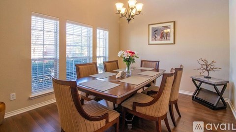 A dining room with a table set for four and a chandelier.