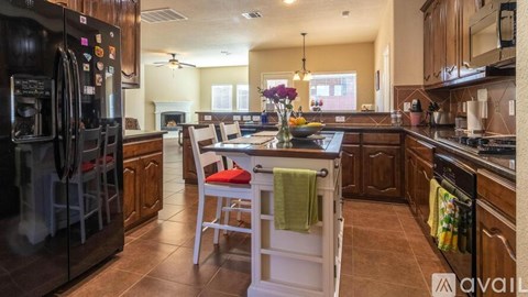 A kitchen with a black refrigerator and brown cabinets.