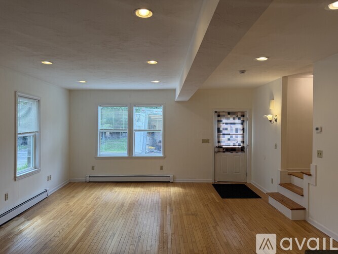 A spacious room with wooden floors and a large window.