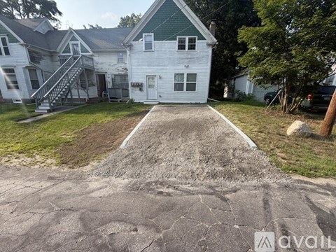 A white house with a green roof and a driveway in front.
