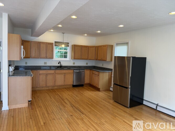 A kitchen with wooden cabinets and a black refrigerator.