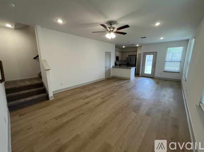 A spacious room with wooden flooring and a ceiling fan.