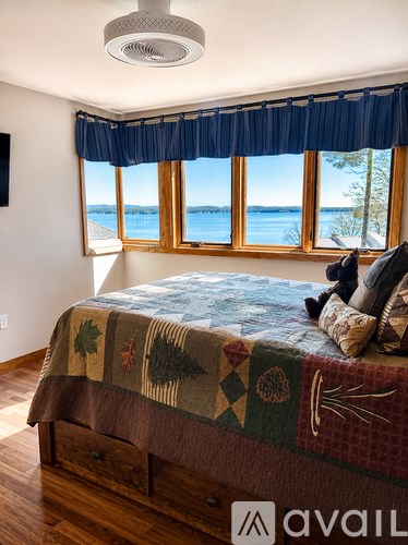 A bedroom with a bed and a window overlooking the water.
