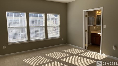 A room with a carpet floor and a door leading to another room.