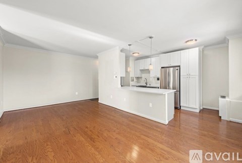 A spacious room with wooden flooring and white walls.
