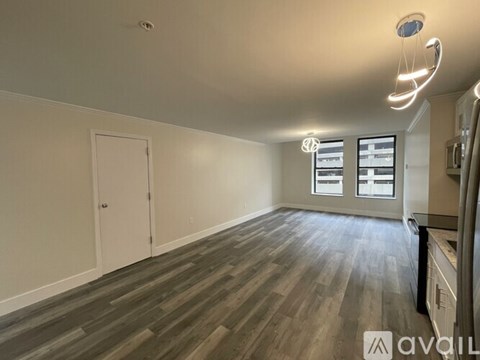 A spacious room with wooden flooring and a window with blinds.