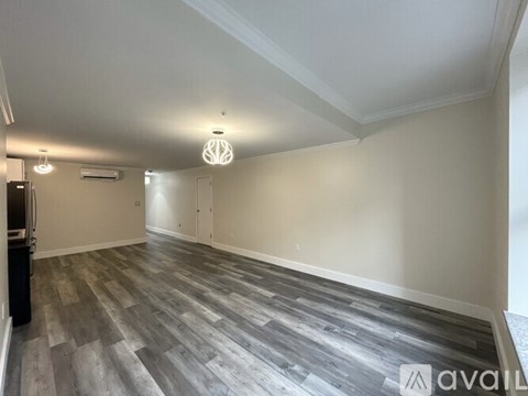 A spacious room with wooden flooring and a ceiling light.
