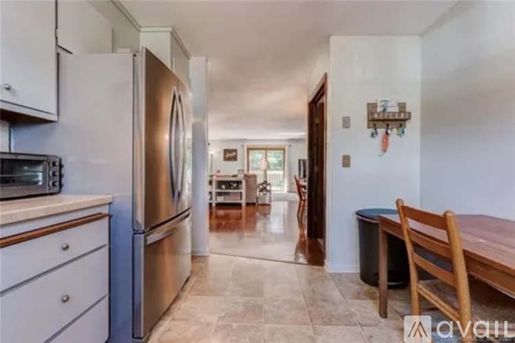 A kitchen with a refrigerator, microwave, and wooden chairs.