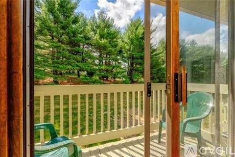 A balcony with a green chair and a view of trees.