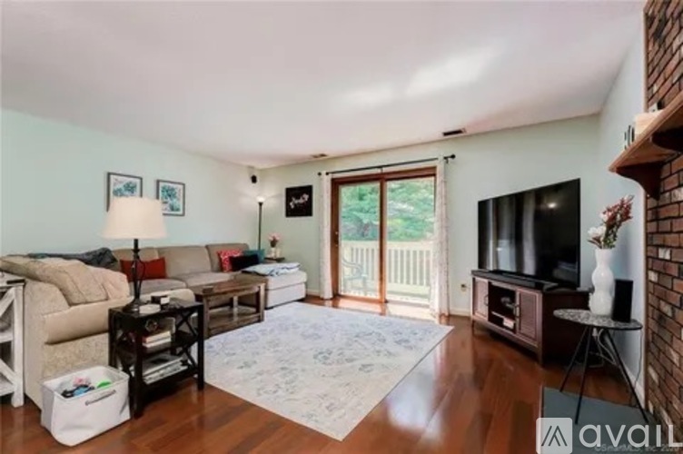 A living room with a couch, a chair, a coffee table, and a television.