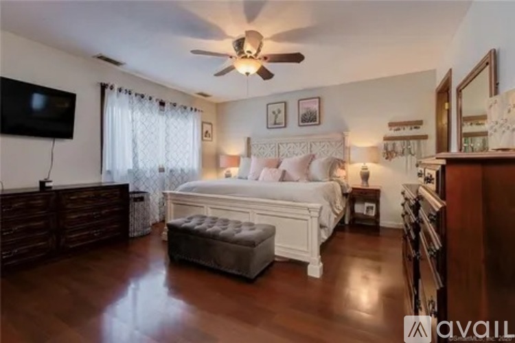 A bedroom with a large bed, a ceiling fan, and a television.