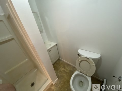 A white toilet in a small bathroom with a white cabinet and a white door.