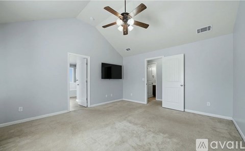 A spacious room with a ceiling fan and a flat-screen TV mounted on the wall.