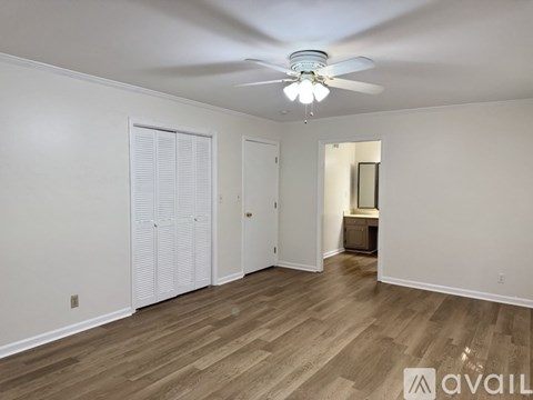 A spacious room with a ceiling fan and wooden flooring.