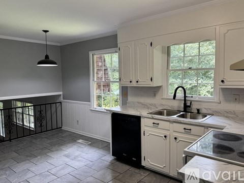 A kitchen with a black dishwasher and white cabinets.