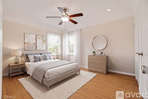 A bedroom with a bed, nightstand, and a fan.