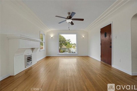 A spacious room with wooden floors and a ceiling fan.