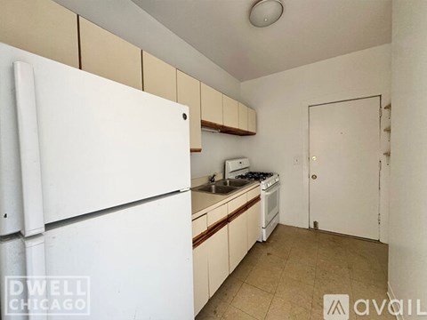 A kitchen with a white fridge and a white door.