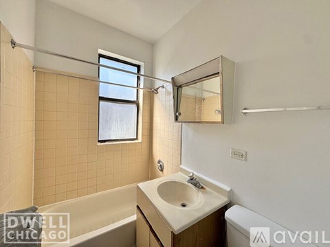 A small bathroom with a tub, sink, mirror and a window.