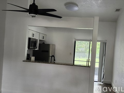 A room with a ceiling fan and a mirror on the wall.
