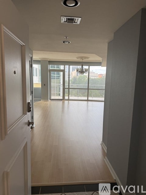 A hallway with a door on the left and a balcony on the right.