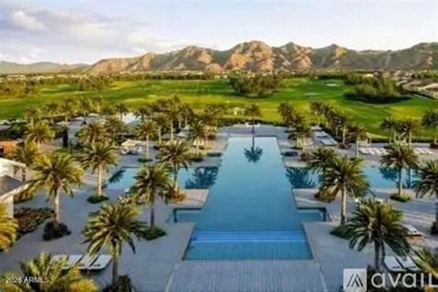 A large pool surrounded by palm trees in the foreground with a mountainous landscape in the background.