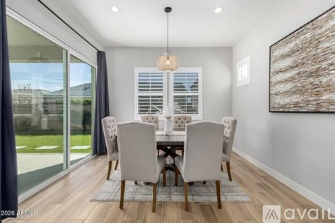 A dining room with a table set for four and a view of the backyard through the sliding glass doors.