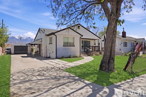 A house with a driveway and a tree in front of it.