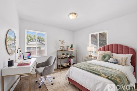 A bedroom with a bed, desk, chair, and window.