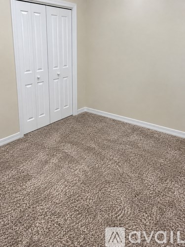 A room with a carpeted floor and a white door.