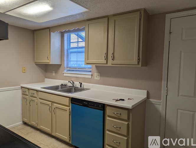 A kitchen with beige cabinets and a blue dishwasher.