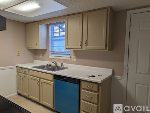A kitchen with beige cabinets and a blue dishwasher.