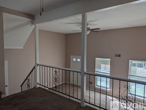 A room with a carpeted floor and a balcony with a metal railing.