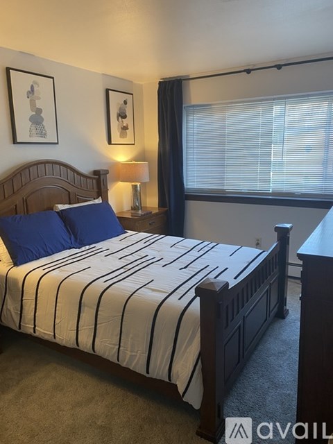 A bedroom with a bed, nightstand, and window.