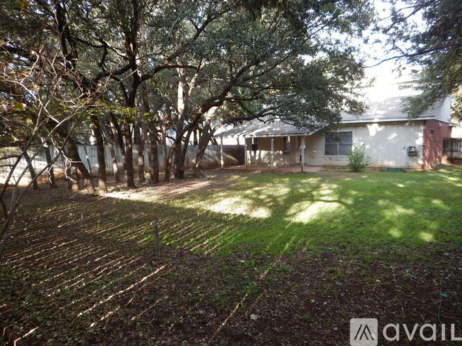 A house is surrounded by trees and has a yard.