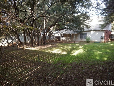 A house is surrounded by trees and has a yard.