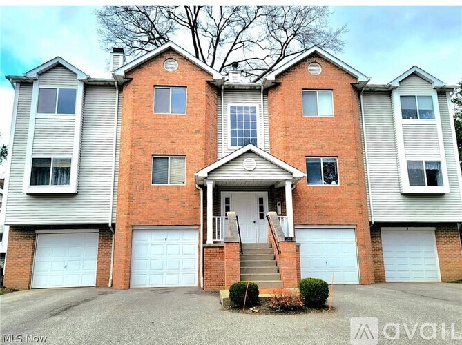 A large brick house with a white garage door is for sale.