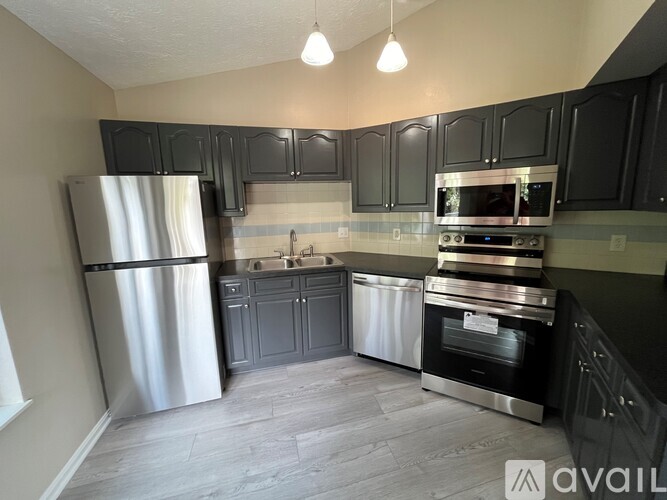 A kitchen with black cabinets and stainless steel appliances.