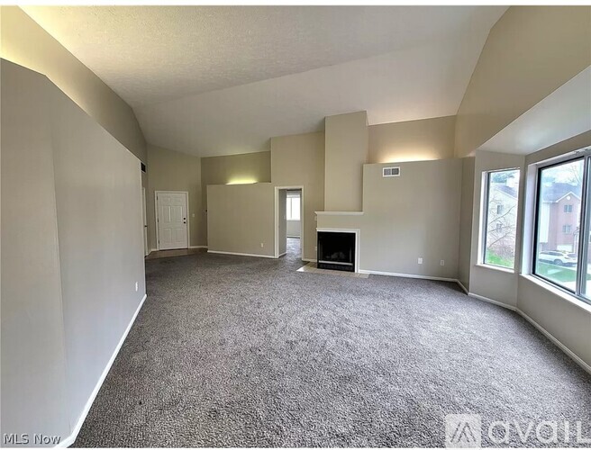 A spacious living room with a fireplace and large windows.
