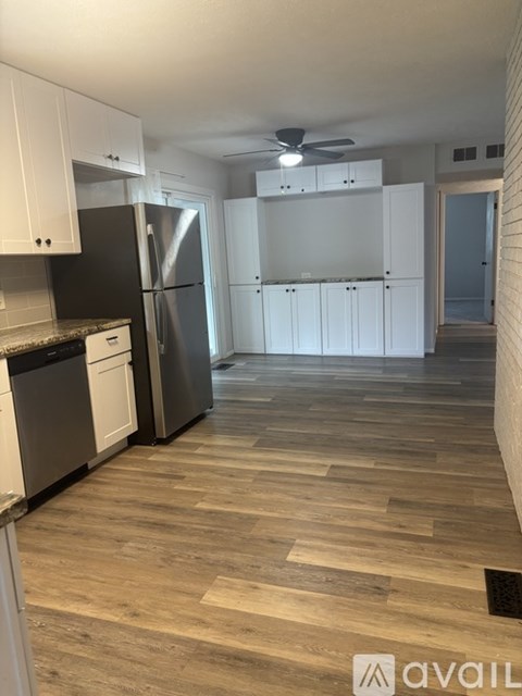 A kitchen with a black refrigerator and white cabinets.