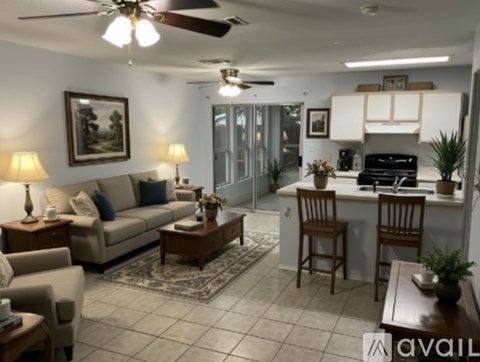 A living room with a couch, chairs, and a ceiling fan.