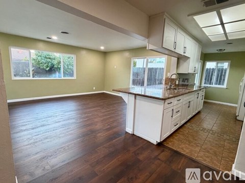 A spacious kitchen with white cabinets and a wooden floor.