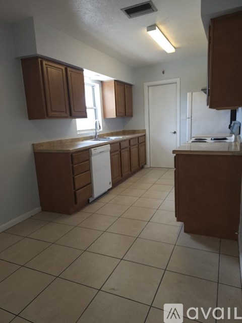A kitchen with brown cabinets and a white dishwasher.