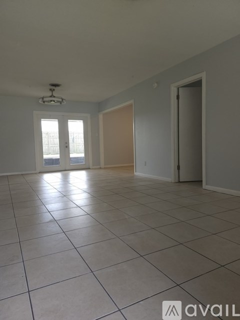 A spacious room with tiled flooring and a ceiling fan.