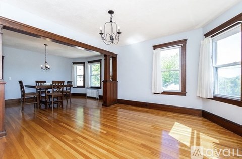 A dining room with a wooden floor and a chandelier.