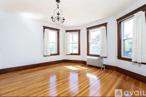 A room with wooden floors and three windows.